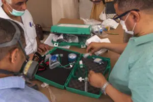 Kit médical sur une table, utilisés par trois personnes.