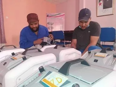 Deux hommes travaillent sur des machines électroniques.